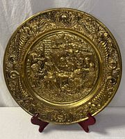 Front view of brass wall plate showing tavern scene and ornate border