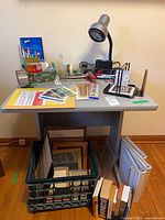 Full view of desk with supplies on surface and frames/books below