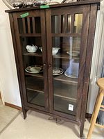 Full view wood and glass display cabinet, doors closed, shelves visible
