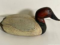 Left side view of carved wooden duck decoy showing painted feather detail and glass eye