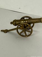 Side view of brass cannon showing wheels and trail