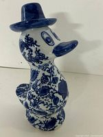 front angled view of blue and white ceramic duck figurine with hat