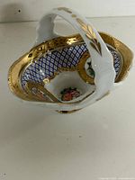 Angled view of Limoges porcelain basket showing interior lattice pattern, floral medallions and gold leaf trim