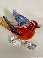 Left front view of multicolour Murano glass bird on clear base