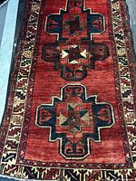 Full length view of red Persian rug with geometric medallions and border