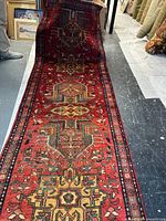 Full length view of red Persian runner showing geometric medallions and borders