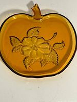 Front view of amber apple-shaped plate showing overall form and floral embossing