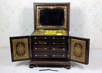 Cabinet open showing mirror, yellow-lined compartment, drawers, open doors with brass inlay