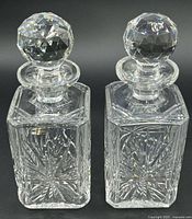 Front view of both square cut crystal decanters with stoppers showing starburst pattern