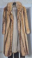 Front view of full-length raccoon fur coat on hanger