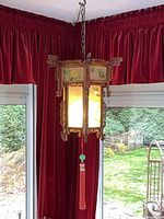 Full view of hanging carved wood lantern lit, showing chain and tassel