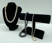 All three pearl necklaces displayed on stands