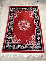Full view of red wool oriental rug showing border, central medallion and fringes