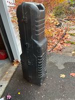 Full front view of upright hard-shell golf travel case showing ridged exterior and latches