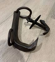 Logging hook and decorative anchor on wood floor showing size and condition