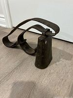 Side view of metal cow bell attached to leather strap