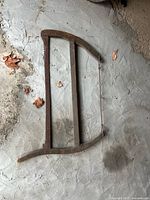 Full view of antique wooden frame bucksaw showing blade, frame, and tension hardware