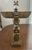 Front view of brass totem pole figurine on wooden surface