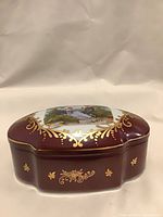 Closed porcelain box showing burgundy color and gold decoration