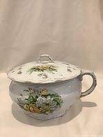 Chamber pot with lid in place showing floral decals and handle