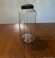Full view of clear glass jar showing cylindrical shape and metal cap
