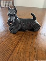 Front-side view of black ceramic Scottie dog figurine on wooden surface
