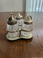 Full view of three cut glass bottles in silver-tone stand