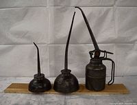 Full view of three metal oil cans on wooden board
