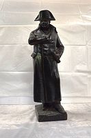 Full view of black plaster Napoleon statue standing on rectangular base