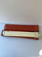 White slide rule inside brown leather sheath