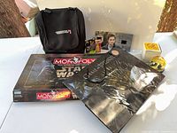 Group shot of entire lot showing bag, Monopoly game, gift bag, cards, Twilight cell, compass, snow globe