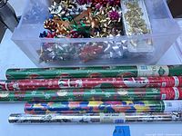 Gift wrap rolls in front of bin filled with bows