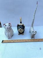 All three wooden cat figurines with ruler for scale