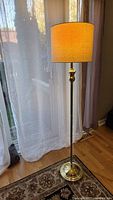 full view of brass floor lamp, shade lit