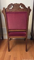 Rear view showing carved wood crest, frame, and wine velvet backrest