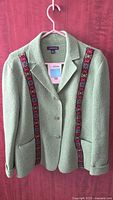 Full front view of green boiled wool jacket on hanger
