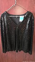Front view of black sequined top on hanger
