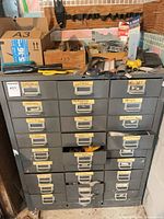 Front view of gray 27-drawer cabinet with labeled drawers, some open