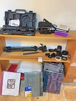 Overall view of scope, camera, tripod, lenses, albums on shelving