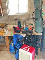 Workbench view showing chairs, cooler, stove, fuel cans, tarp bag