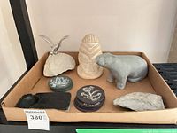 Tray displaying all items: soapstone hippo, abstract totem, whale tail sculpture, two stacks of etched coasters, ashtray, rough stone