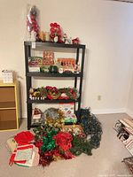 Shelving unit and floor showing assorted Christmas ornaments, garlands, lights, placemats and décor pieces