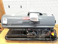 Side view of grey Dyna-Glo Delux 80,000 BTU forced-air heater on base