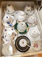 Drawer containing nine inverted teacups on matching saucers plus creamer and sugar