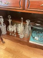 View of two crystal decanters, five liqueur glasses, stack of bowls, clear glass tray and blue ceramic tray