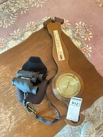 Nikon binoculars with case beside Taylor wooden barometer on table
