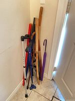 Group of canes, walking sticks, yardstick and umbrellas leaning in corner