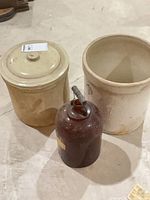 Three items: lidded crock left, unlidded crock right, amber jug front