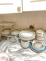 Full lot showing stacked plates, bowls, mugs on wire racks