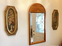 Mirror centered between two framed prints on wall